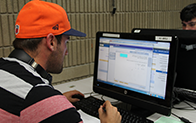 student wearing orange baseball cap and doing work on computer
